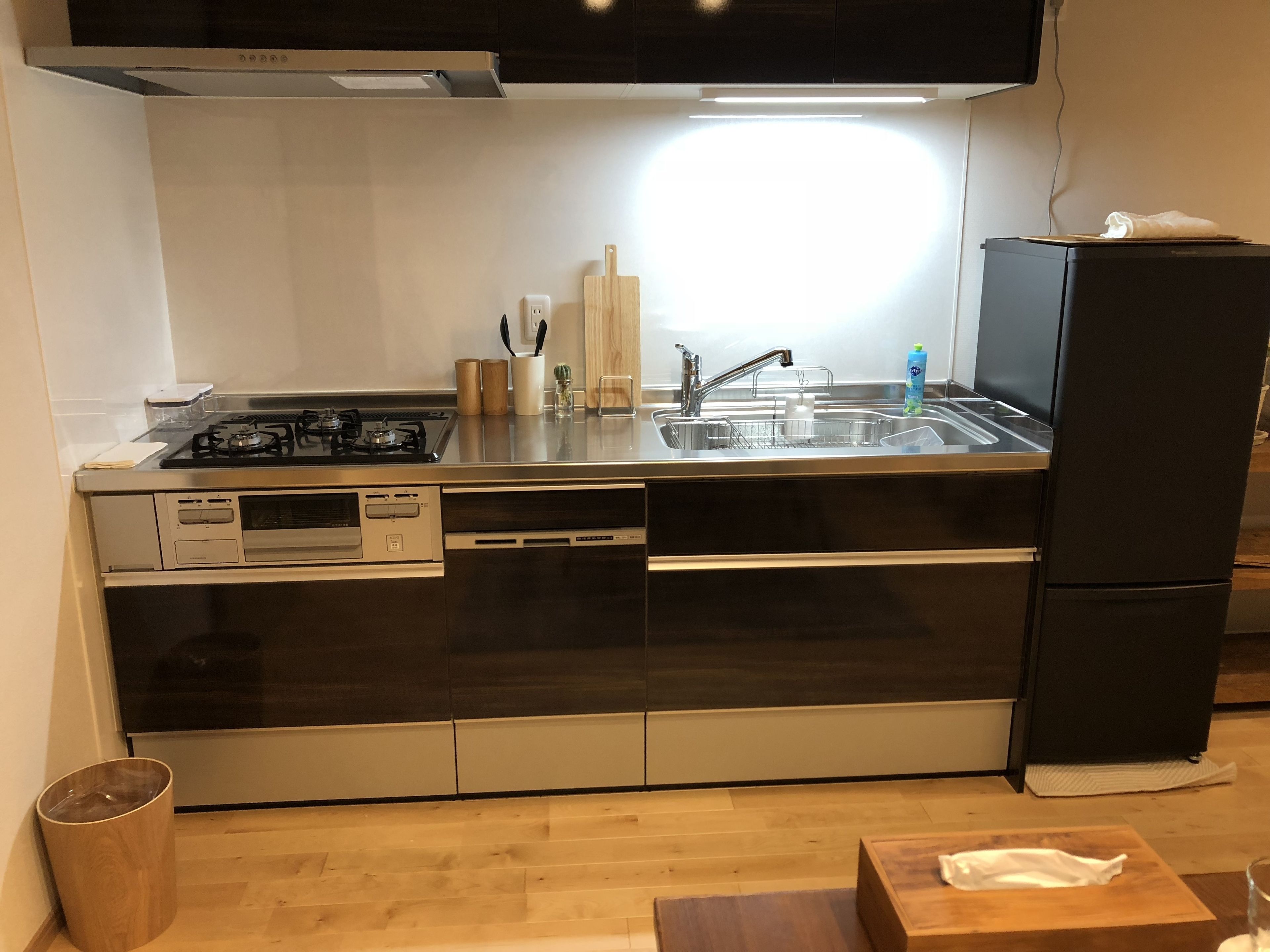 Een moderne keuken met een gasfornuis, een roestvrijstalen spoelbak en een zwarte koelkast.