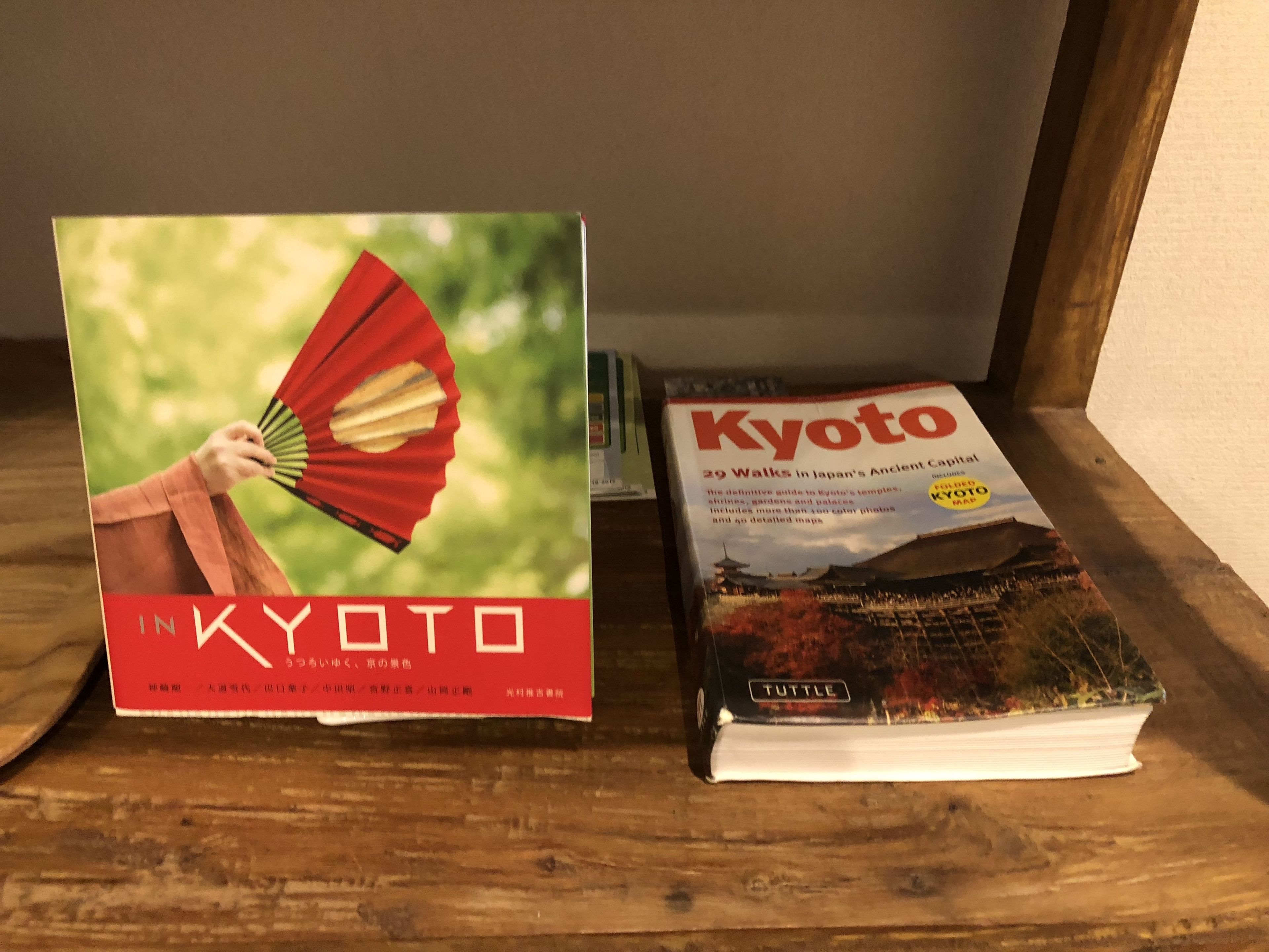 Dos libros, uno titulado 'En Kioto' y otro 'Kioto', sobre una estantería de madera.