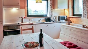 A cozy kitchen with wooden cabinets, a dining table, and a window overlooking greenery.