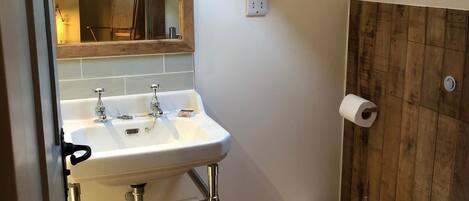 Une petite salle de bain avec un puits de lumière, un lavabo avec un miroir et des toilettes.