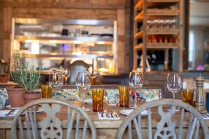 A restaurant setting with a wooden table set for dining, potted plants, and a variety of glassware. - Black Horse (Arundel)