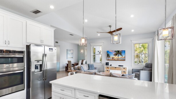 Una cocina moderna con electrodomésticos de acero inoxidable, una isla grande y un comedor con vistas a palmeras.