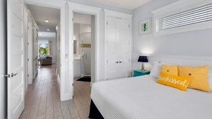 Habitación de hotel con cama, mesita de noche y vistas al baño y al pasillo.