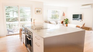 A modern kitchen with a large island, sliding glass doors to a balcony, and a dining area with a sofa and chairs. - Gorgeous High-End Townhome - Easy Walk to Pearl Street, Campus, Google (Boulder)