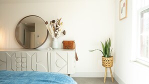 A bedroom with a bed, a dresser with a mirror, a vase with flowers, a brown bag, and a potted plant. - Gorgeous High-End Townhome - Easy Walk to Pearl Street, Campus, Google (Boulder)