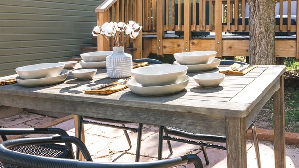 An outdoor dining area with a wooden table set with white bowls and a vase with dried flowers. - Gorgeous High-End Townhome - Easy Walk to Pearl Street, Campus, Google (Boulder)