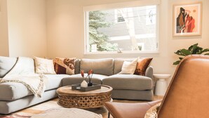 A living room with a grey sofa, a round coffee table, and a brown armchair. - Gorgeous High-End Townhome - Easy Walk to Pearl Street, Campus, Google (Boulder)