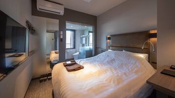 A hotel room with a large bed, a bedside table, a mirror, and a bathroom visible through an open door.