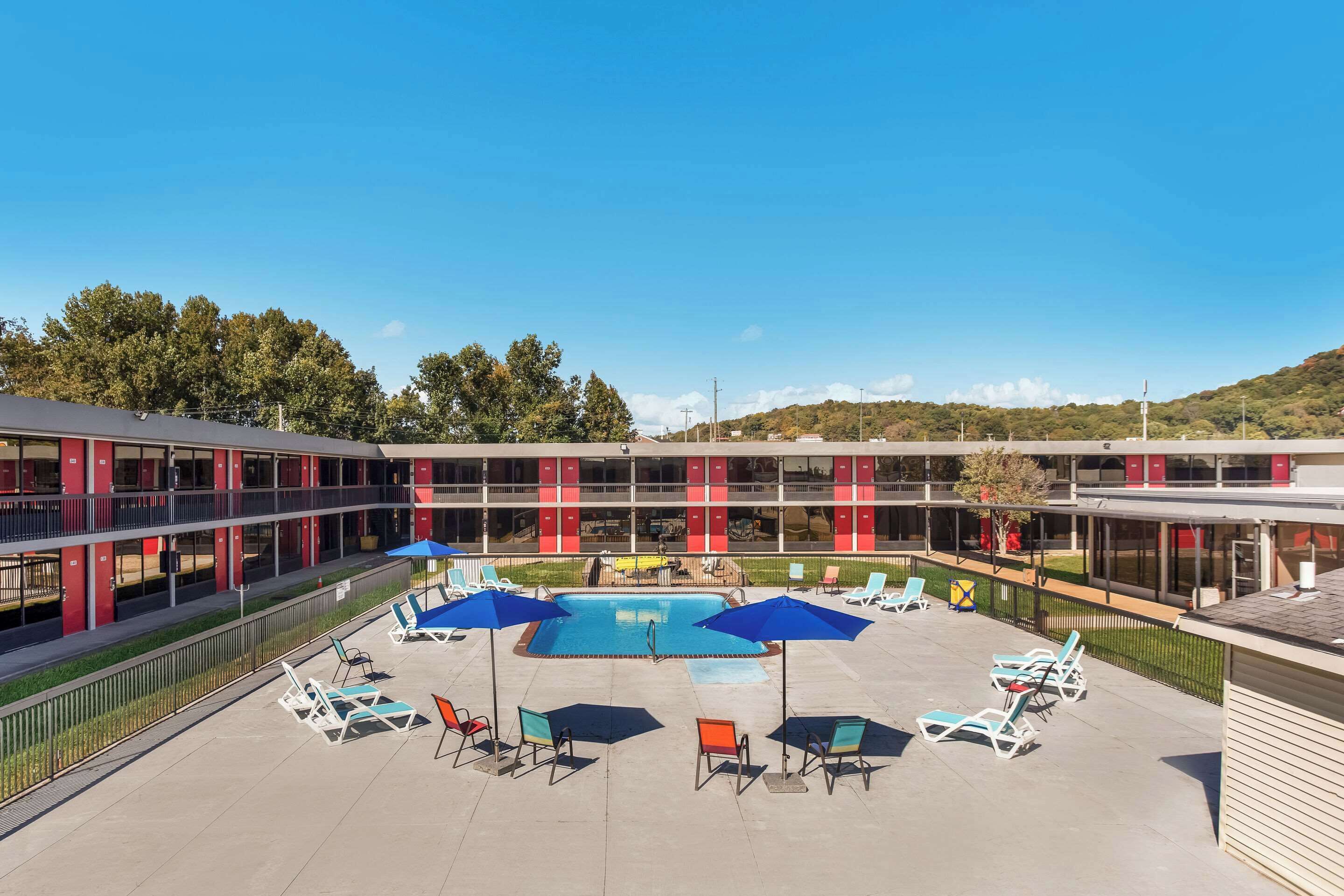 A hotel with a pool area, sun loungers, and umbrellas.