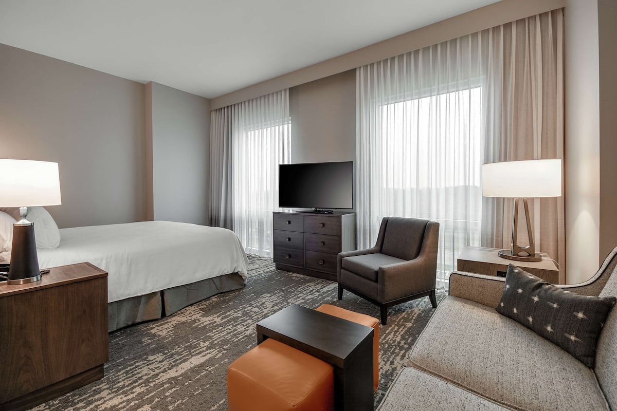 Een hotelkamer met een bed, een televisie, een bureau, een stoel en een bank.