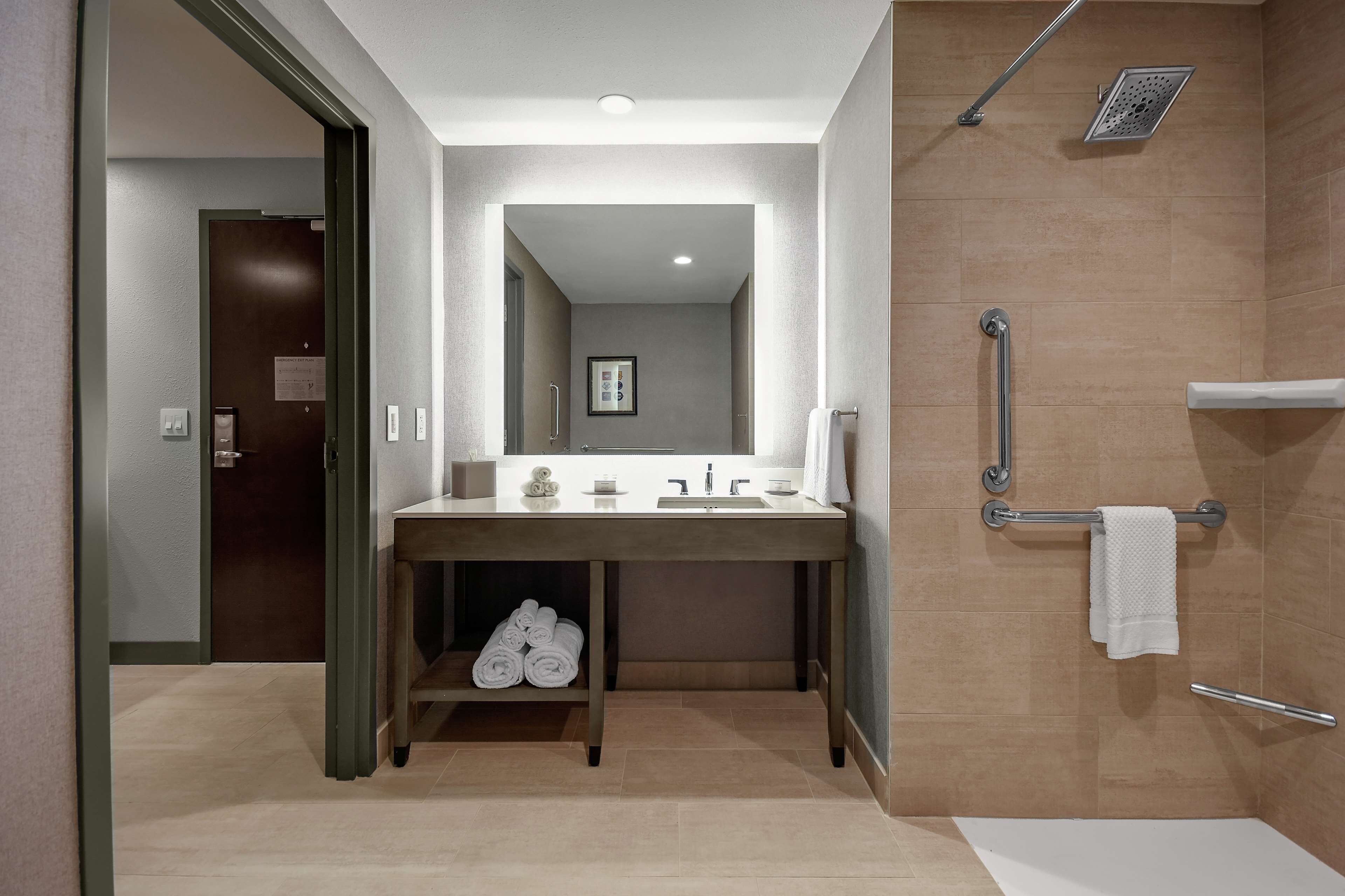 A modern bathroom with a shower, a sink with a mirror, and a towel rack.