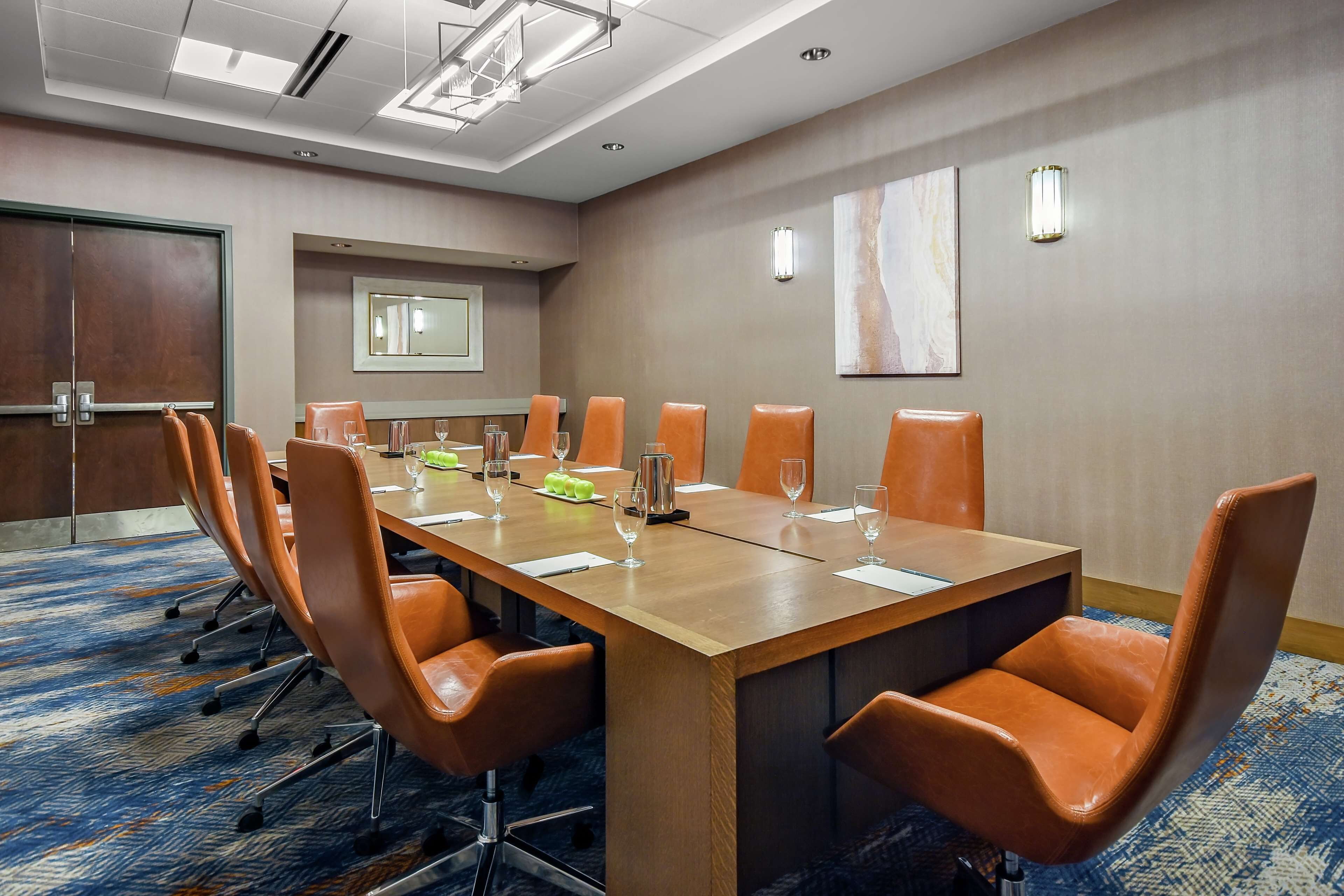 A conference room with a long table, orange chairs, and a carpeted floor.