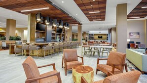 A spacious lobby with a bar area, seating arrangements, and a television screen.