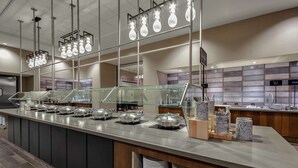 A buffet area with multiple serving stations, glass railings, and a variety of food containers.