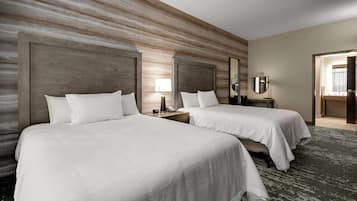 Habitación de hotel con dos camas, cabeceros de madera, un espejo grande y piso alfombrado.