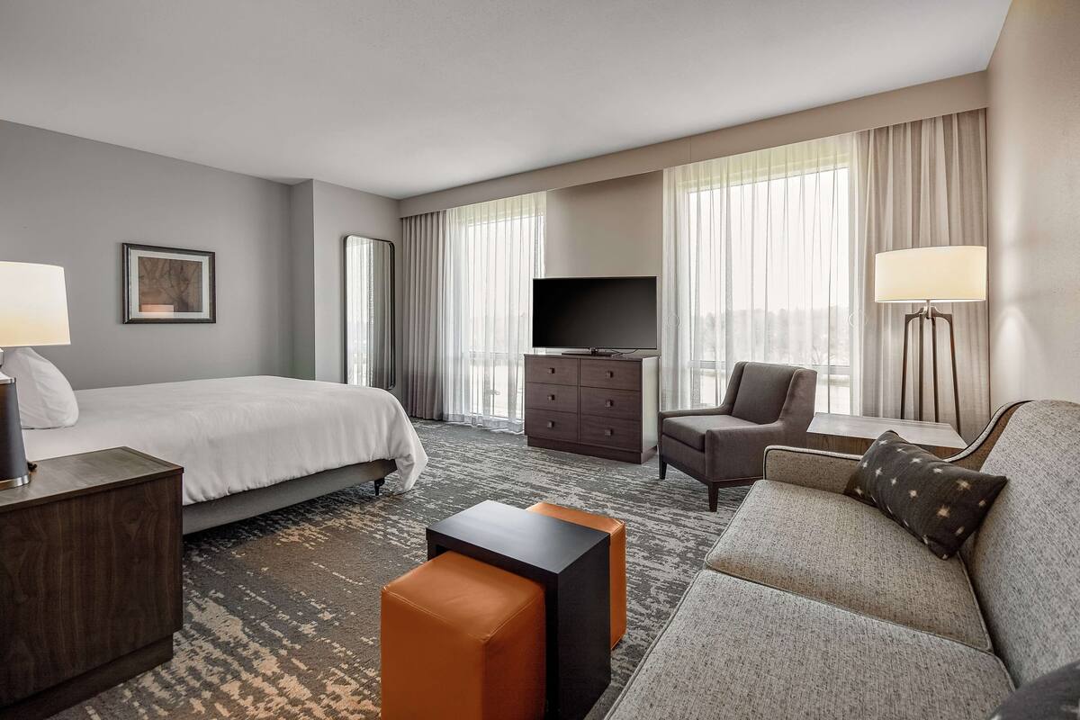Een hotelkamer met een bed, een bank, een televisie, een bureau en een lamp.