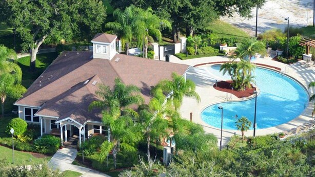 A residential property with a swimming pool, surrounded by lush greenery and a well-maintained lawn. - Mickey an Minnie House (Kissimmee)
