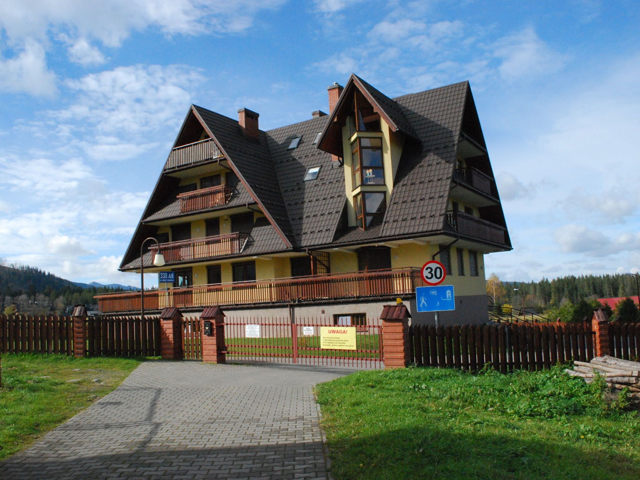 Un bâtiment de style chalet traditionnel, doté d’un toit en pente, de plusieurs balcons et d’une entrée fermée par un portail.