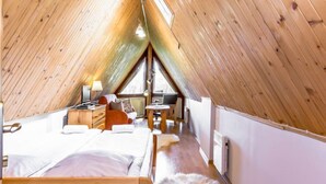 A cozy attic bedroom with a sloped ceiling, a bed, a desk, and a chair. - Giewont View by Interhome (Zakopane)