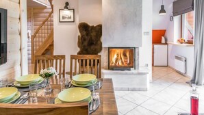 A cozy interior with a fireplace, wooden furniture, and a dining area set for four. - Giewont View by Interhome (Zakopane)