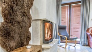 A cozy living room with a fireplace, a leather armchair, and a fur-covered wall. - Giewont View by Interhome (Zakopane)