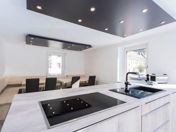 A modern kitchen with a central island, built-in oven, and a window providing a view of the city.