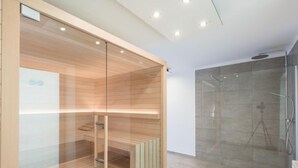 Un baño moderno con ducha de vidrio, paneles de madera y un perchero visible.