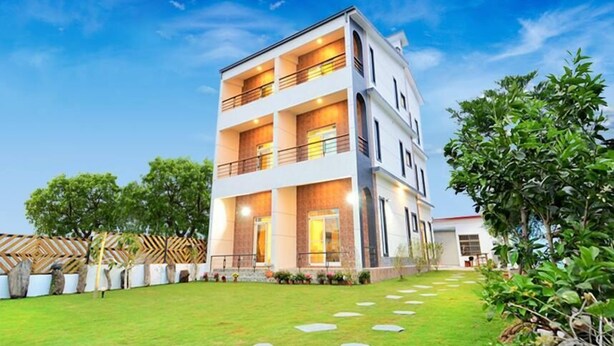 A multi-story building with a well-maintained lawn, stone pathway, and a fence with geometric patterns. - Stone Home Bed and Breakfast (Taitung)