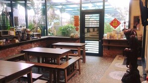 A cozy cafe with wooden tables and chairs, a counter with various items, and a view of greenery outside. - Stone Home Bed and Breakfast (Taitung)