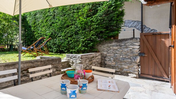 An outdoor patio with a table set for dining, a wooden door, and a stone wall. - Jouvenceaux by Interhome (Sauze d'Oulx)