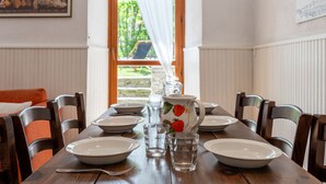 A dining table set with plates, glasses, and a pitcher, with a view of greenery outside. - Jouvenceaux by Interhome (Sauze d'Oulx)