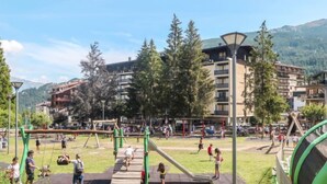 A playground with various equipment, surrounded by buildings and trees. - Jouvenceaux by Interhome (Sauze d'Oulx)