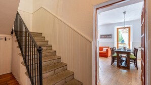 A staircase with a wooden handrail leading to a room with a dining table and chairs. - Jouvenceaux by Interhome (Sauze d'Oulx)