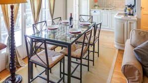 Una cocina moderna con armarios blancos, una mesa de comedor de cristal y un sofá color beige.
