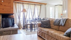 Una sala de estar acogedora con chimenea, un sofá, una mesa de centro y un comedor con mesa y sillas.