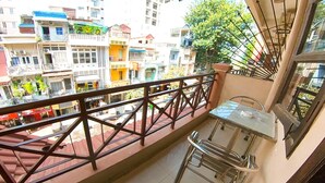 Ein Balkon mit Metallgeländer, einem kleinen Tisch und einem Stuhl.