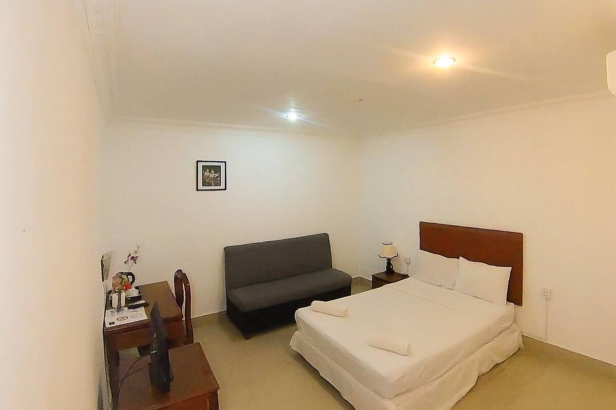 Une chambre d’hôtel avec un lit, un canapé, un bureau et une table de chevet.