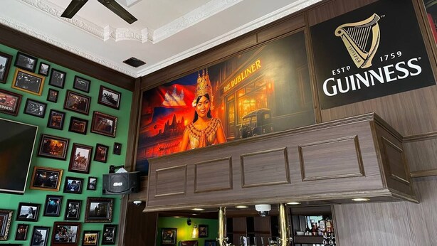 Ein Hotelinterior mit Guinness-Logo, Deckenventilator und einer Wand mit gerahmten Bildern.