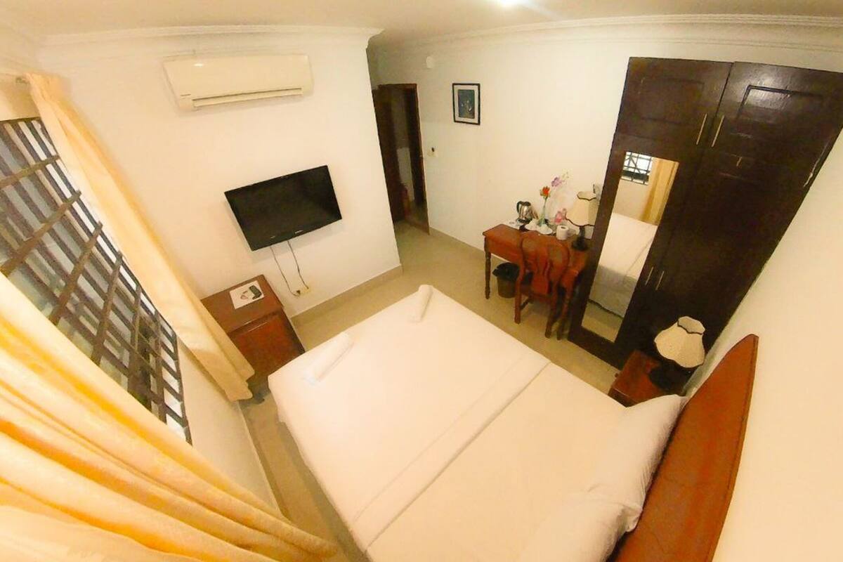 Une chambre d’hôtel équipée d’un lit, d’un bureau, d’une chaise, d’une télévision et d’une armoire.