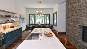 A modern kitchen with a long island, built-in appliances, and a stone accent wall.