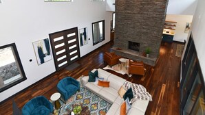 A spacious living room with a fireplace, wooden flooring, and modern furniture.