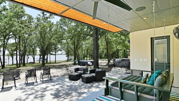 A modern outdoor seating area with a view of a lake, surrounded by trees.