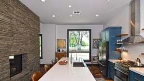 A modern kitchen with a large island, a built-in stove, and a stone accent wall.
