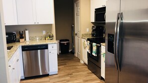A compact kitchen with white cabinets, a stainless steel dishwasher, a refrigerator, and a microwave. - 3BR/2BA Lake Mariam Home Near LEGOLAND with Kitchen & Laundry_1724 (Winter Haven)