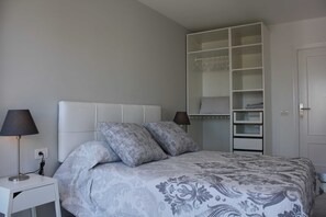 A bedroom with a bed, bedside lamps, a wardrobe, and a door.