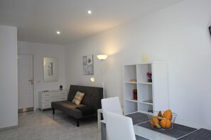 A modern living room with a sofa, a dining table, and a white cabinet.