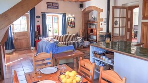 A rustic interior with a dining area, a striped sofa, and a kitchen with a tiled backsplash. - Mas Troumpill by Interhome (Argelès sur Mer)