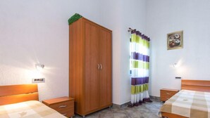 Une chambre avec deux lits, une armoire, un rideau et un tableau au mur.