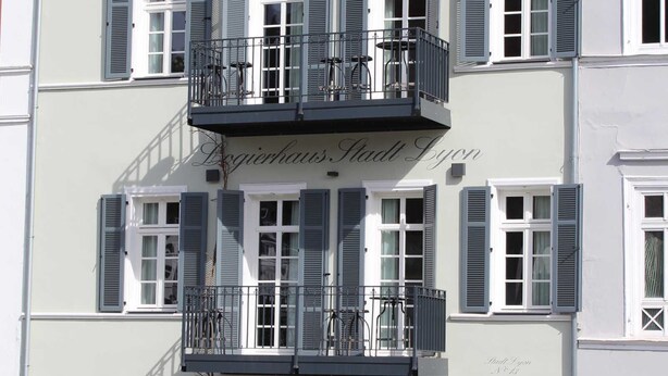 Un edificio de varios pisos con balcones, una escalera y un letrero que dice "Logierhaus Stadt Lyon".