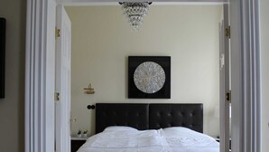 Un dormitorio con cama, una araña, una obra de arte redonda y una mesita de noche.